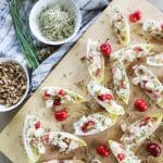Delicious shrimp salad served in crisp endive leaves topped with fresh cherries and herbs, perfect for a light appetizer or summer party.