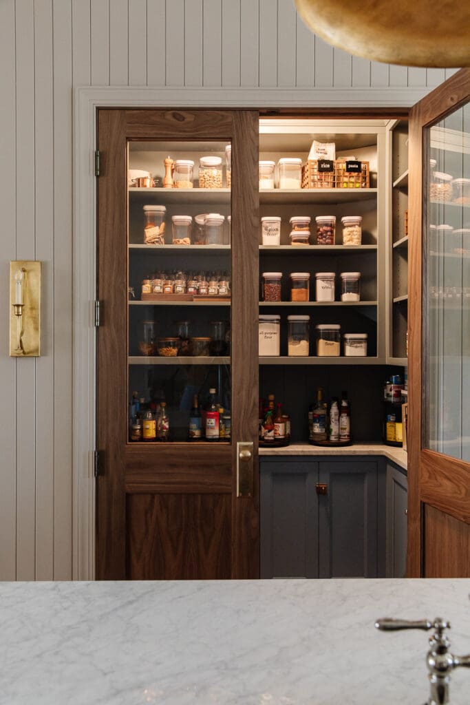 A beautiful double-door pantry with clear glass and decanted products