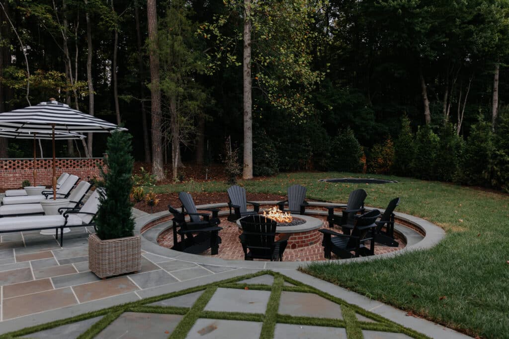 Sunken fire pit with herringbone brick floor and black adirondack chairs