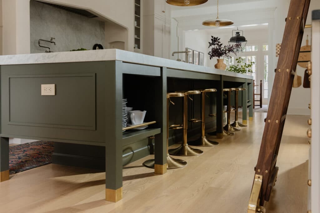 Modern kitchen island with a white marble countertop, green base, and gold accents, featuring bar stools in a contemporary home setting.