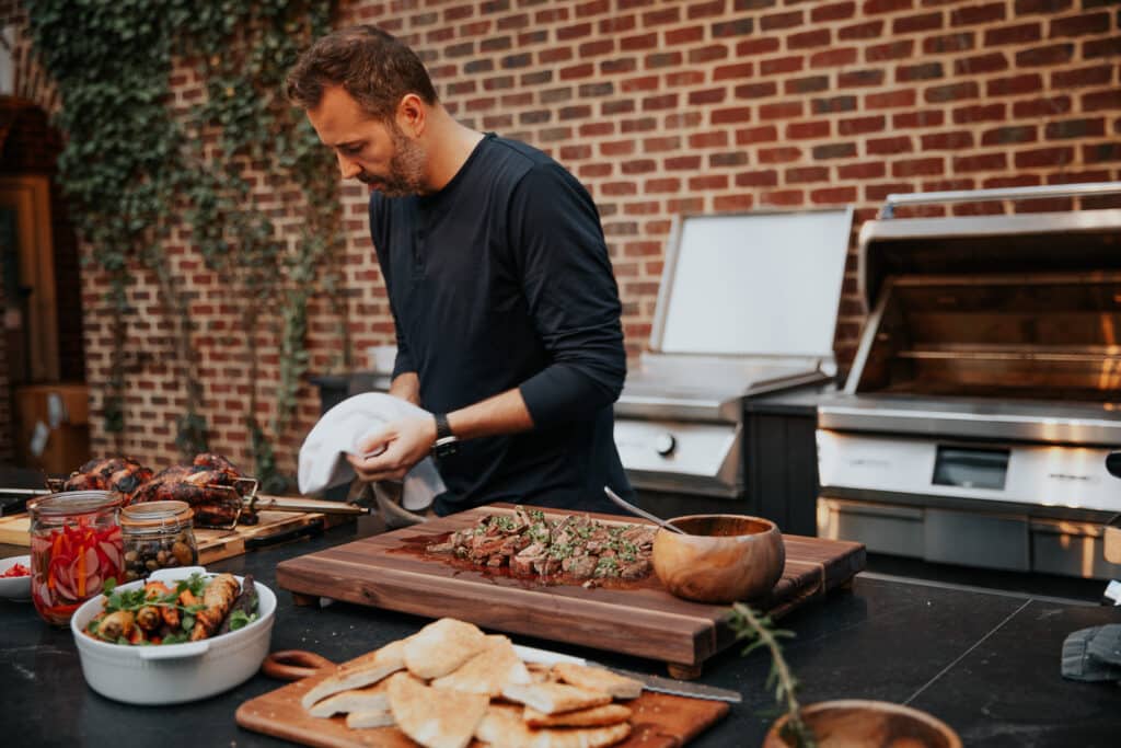 Man preparing steak on outdoor grill in backyard.
