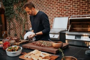 Man preparing steak on outdoor grill in backyard.