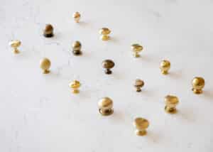Various styles of brass cabinet knobs laid on a kitchen island