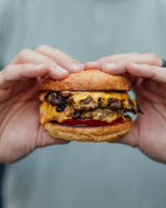 Two hands holding a smash burger