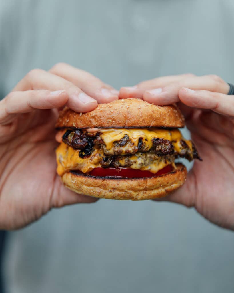 Two hands holding a smash burger