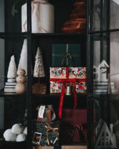 Festive Christmas gift boxes on black display cabinet, holiday home decor ideas, colorful wrapped presents, and seasonal decorations for Christmas celebration.