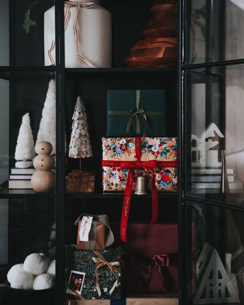 Festive Christmas gift boxes on black display cabinet, holiday home decor ideas, colorful wrapped presents, and seasonal decorations for Christmas celebration.