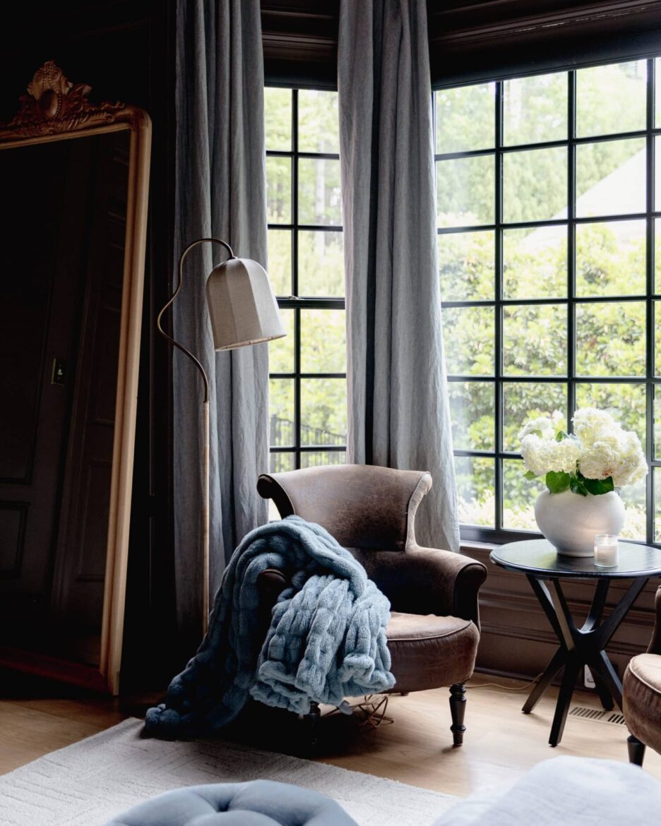 Inviting reading nook featuring a plush armchair, soft throw blanket, and large window with flowing curtains, perfect for relaxing with a book.