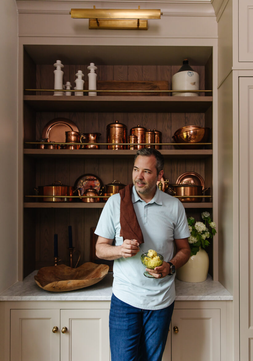 Dairy-free golden milk ice cream served in a glass bowl, with a man holding a spoon and enjoying the treat in a stylish kitchen. Perfect for healthy, dairy-free dessert options.
