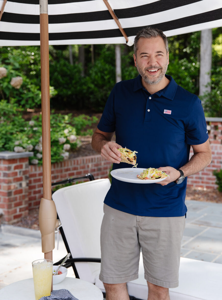Chris Marcum enjoying outdoor dining with a plate of sandwiches during a sunny day.
