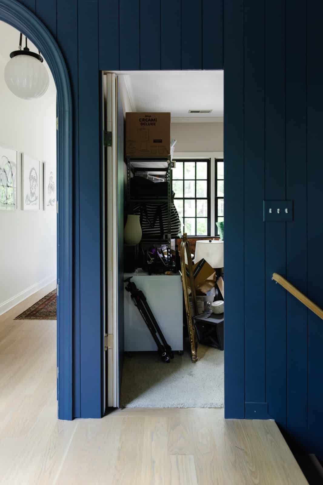 Storage room with stacked boxes, furniture, and supplies in a small space, showing disorganized storage solutions.