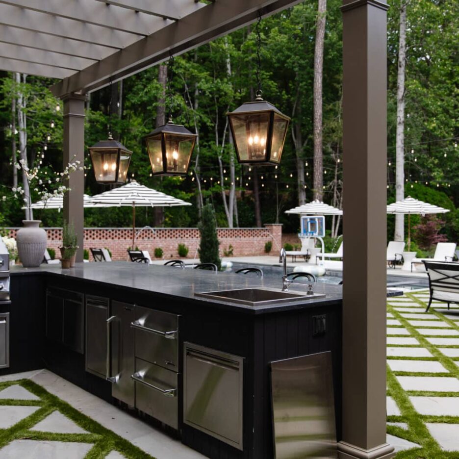 Charming outdoor bar area featuring hanging lanterns, string lights, and a sleek black countertop, perfect for outdoor gatherings and summer evenings.