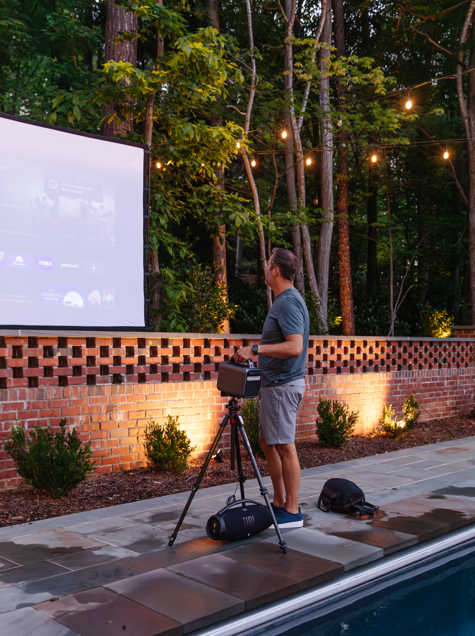 Chris Loves Julia | Chris setting up the projector for an outdoor movie pool party at night