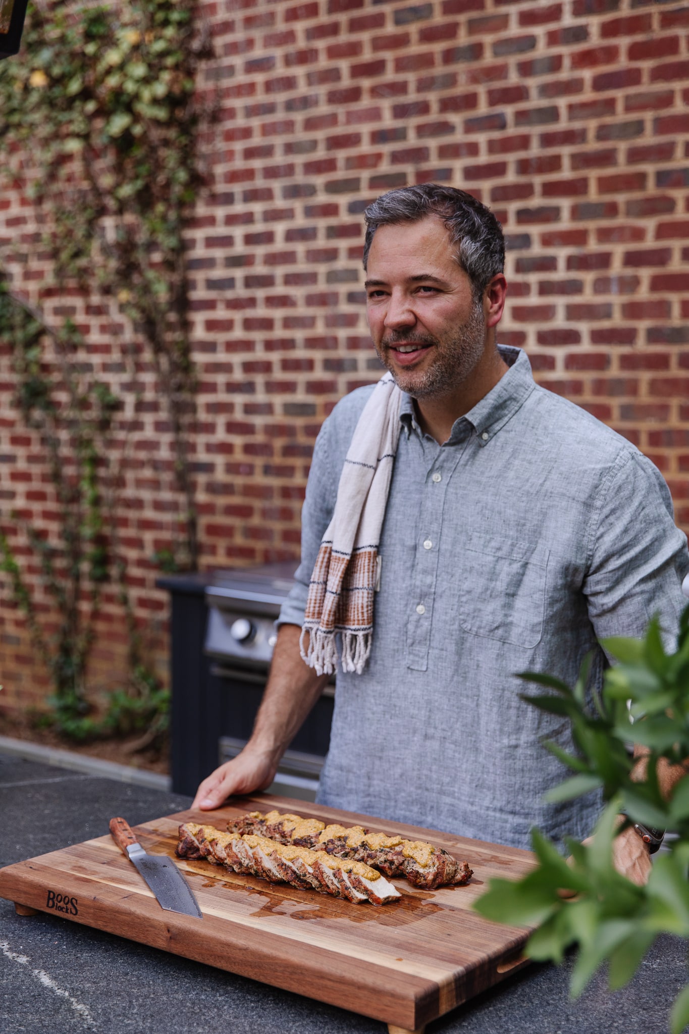 Chris Loves Julia | Chris in front of a wood cutting board featuring Grilled Pork Tenderloin with Macadamia Nut Pesto