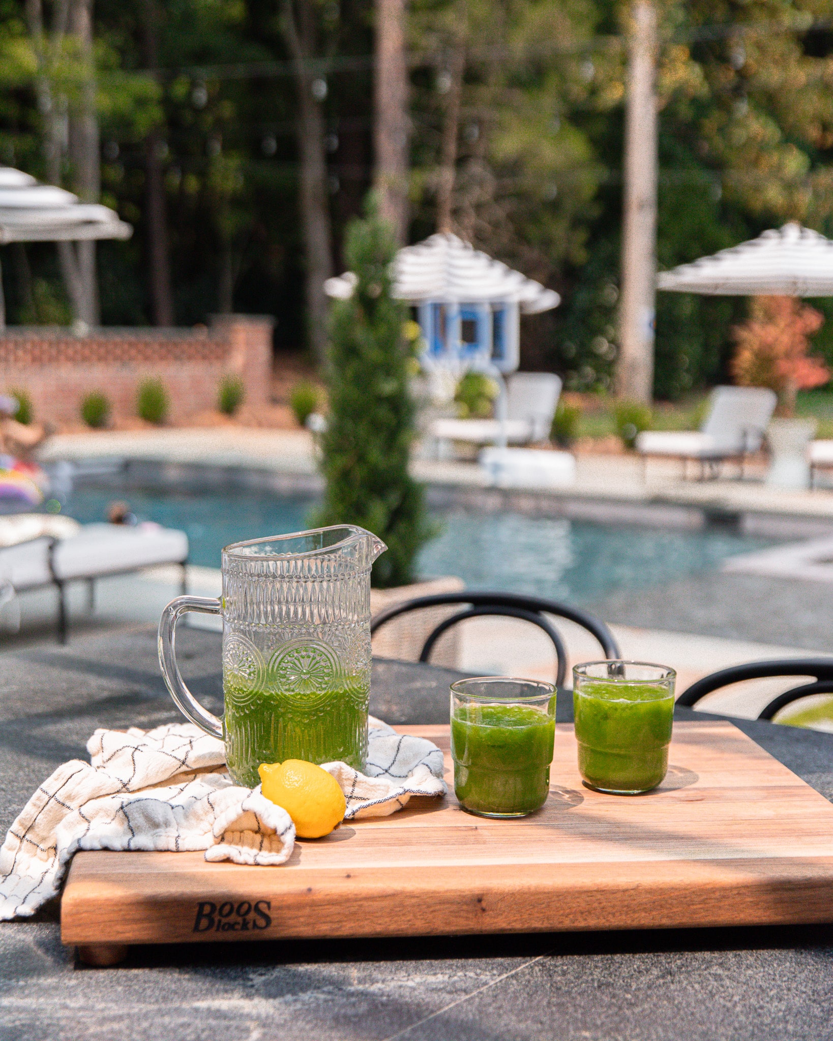 Green juice in a pitcher next to two glass cups