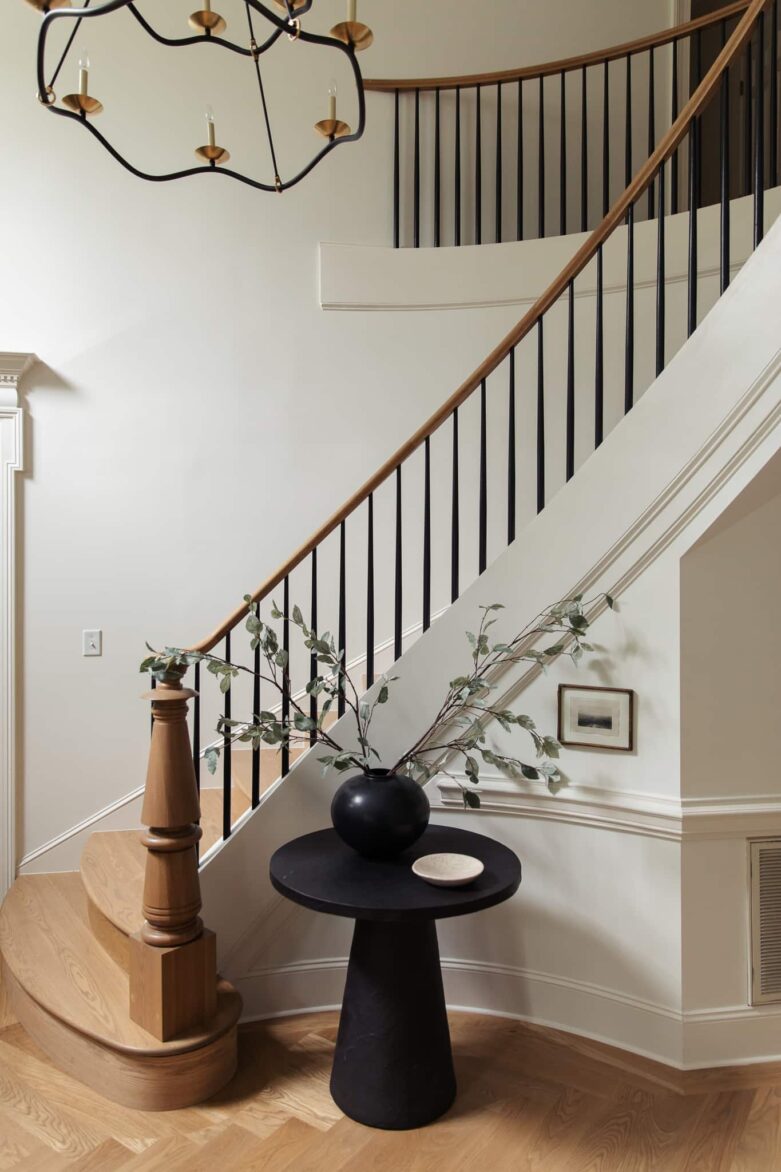 Elegant staircase with black metal balusters and wooden handrail in a stylish home.