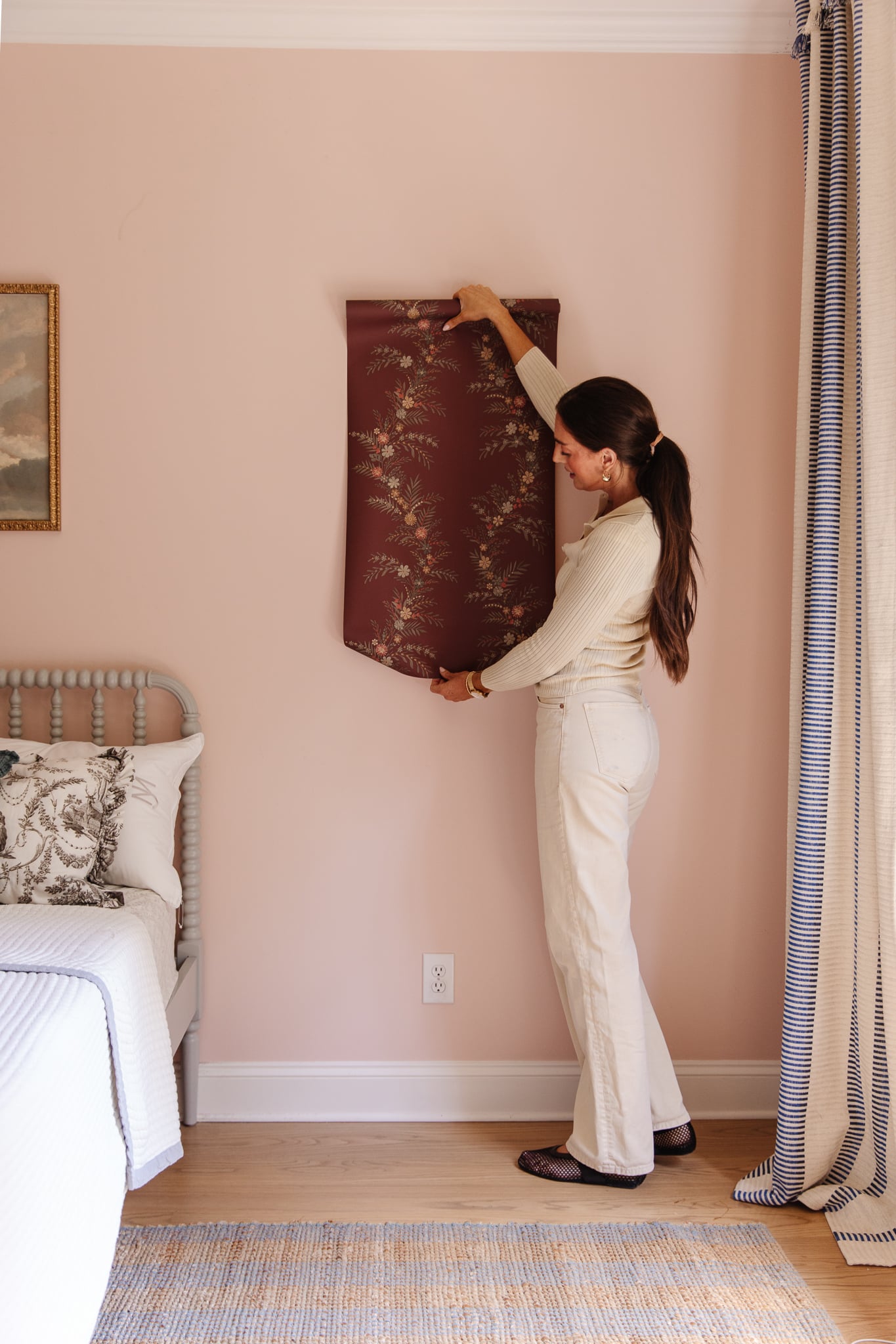 Chris Loves Julia | Julia unrolling a roll of CLJ x WallPops Posy Collection Wallpaper in Cranberry