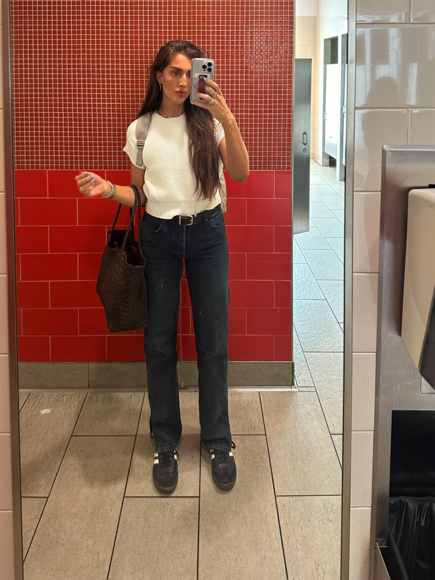 Julia in jeans and white tee in a red bathroom