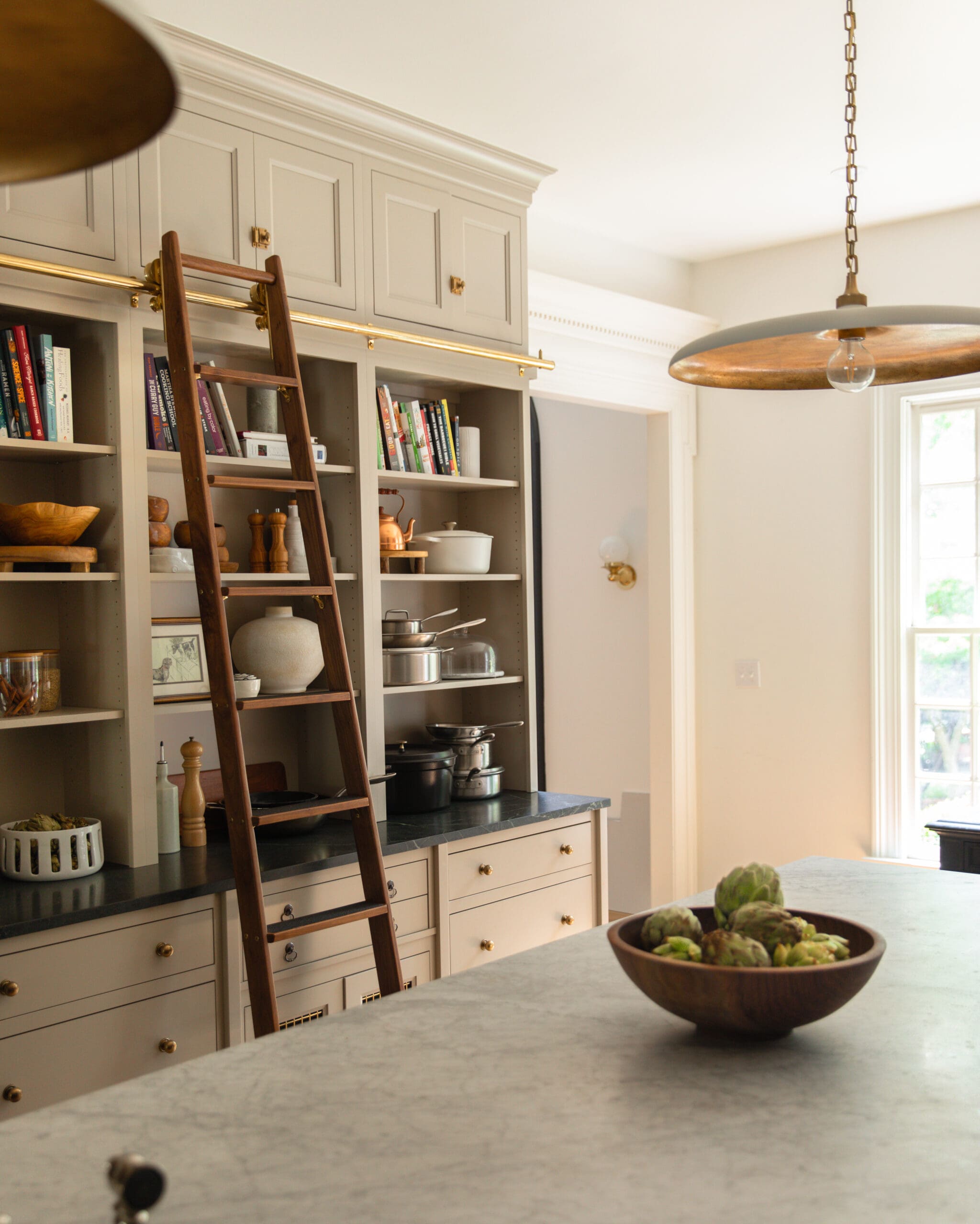 Chris Loves Julia | Kitchen island styled with a wooden bowl filled with artichokes