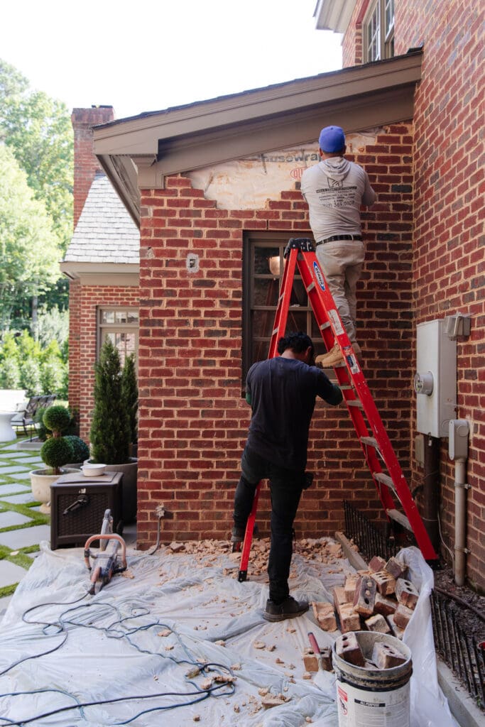 Contractors opening a brick wall and window to turn it into a door