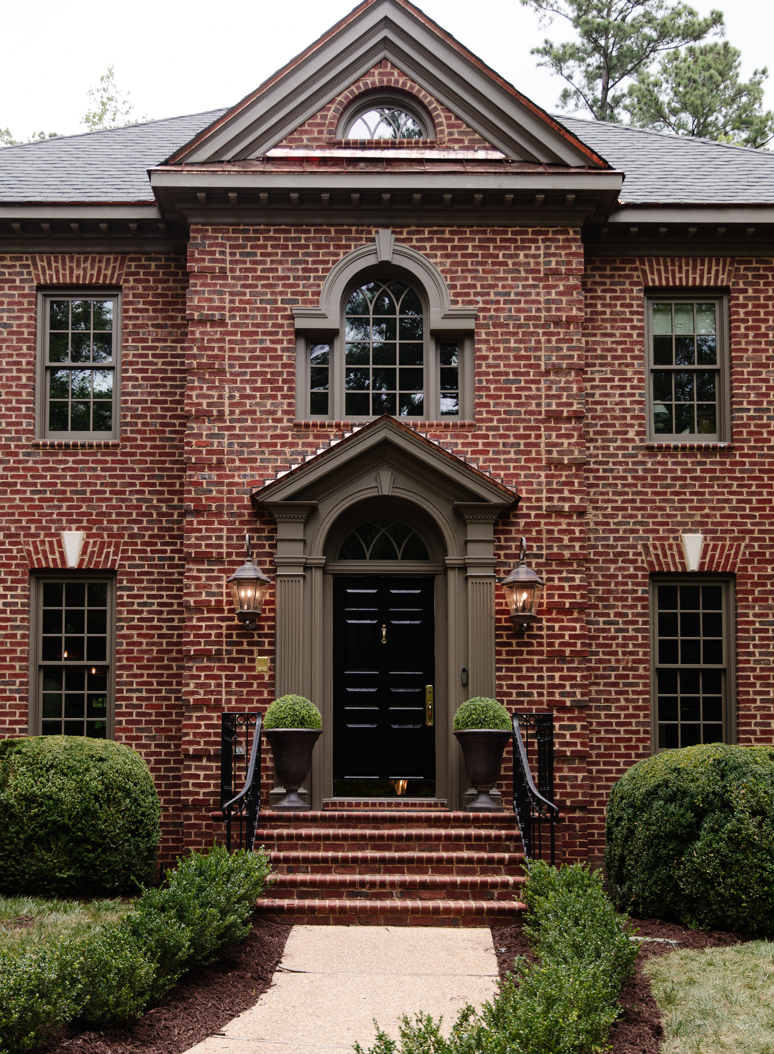 Chris Loves Julia | The front door painted in Tricorn Black by Sherwin Williams with bronze tall planters flanking it