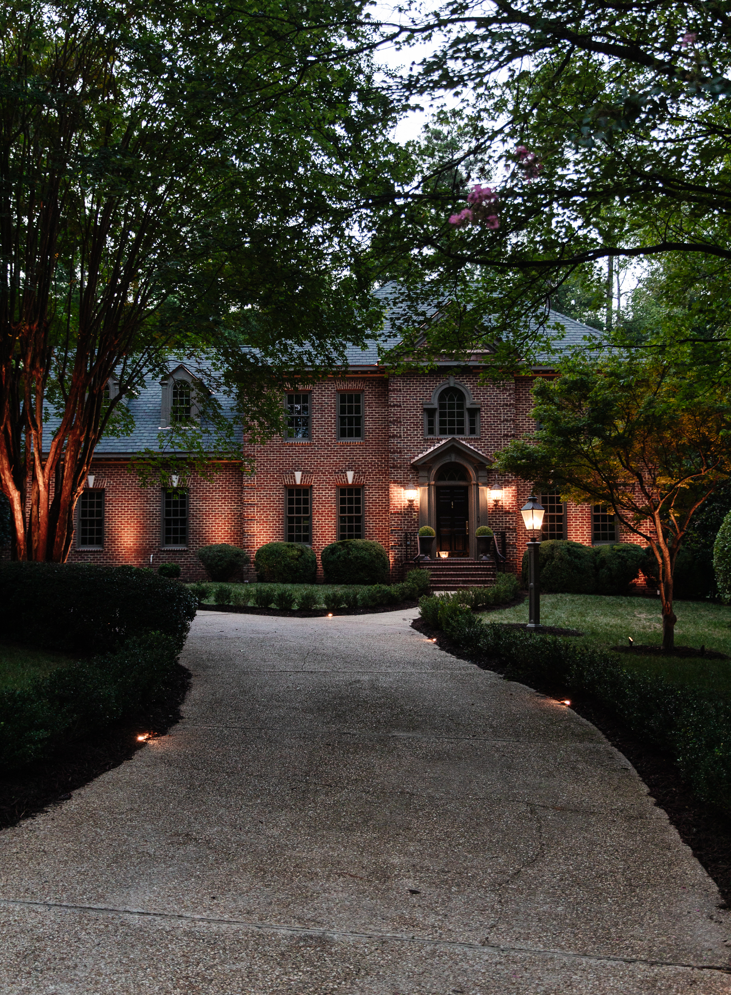 Chris Loves Julia | Modern Colonial house front exterior with landscape lighting at dusk