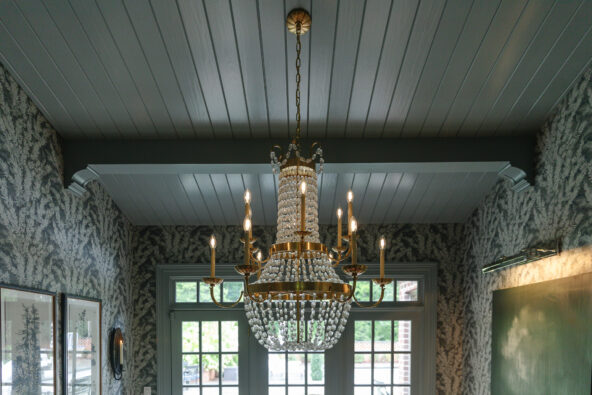 A dining room with ceiling beams, planks, and corbels painted smokey gray-blue