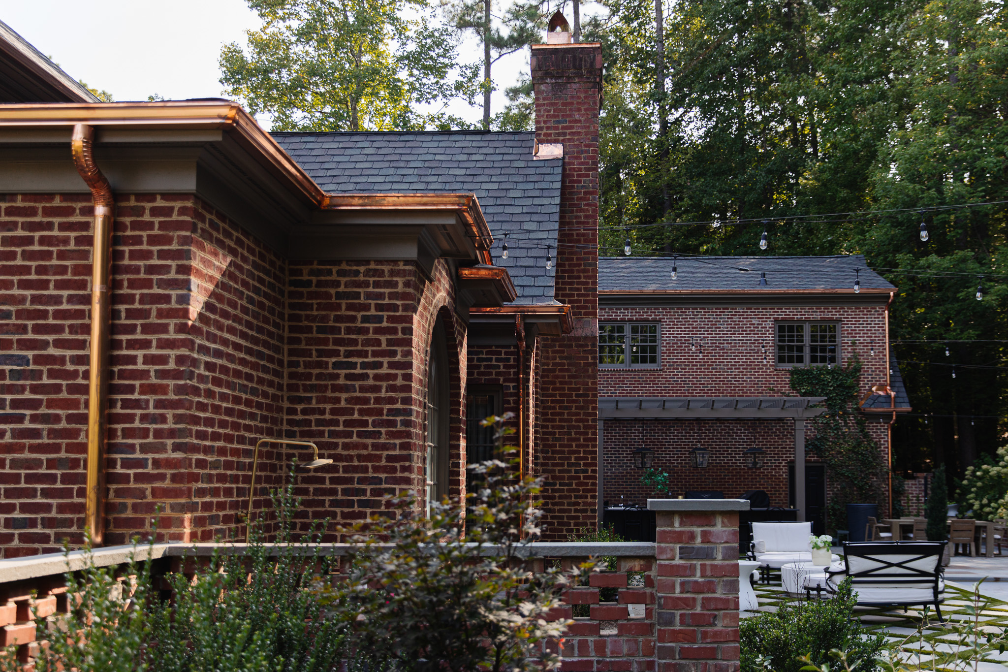 Chris Loves Julia | Backyard of a traditional brick house with new copper gutters and chimney hood