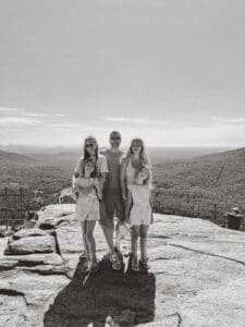 Family enjoying a scenic outdoor view from a rocky overlook.