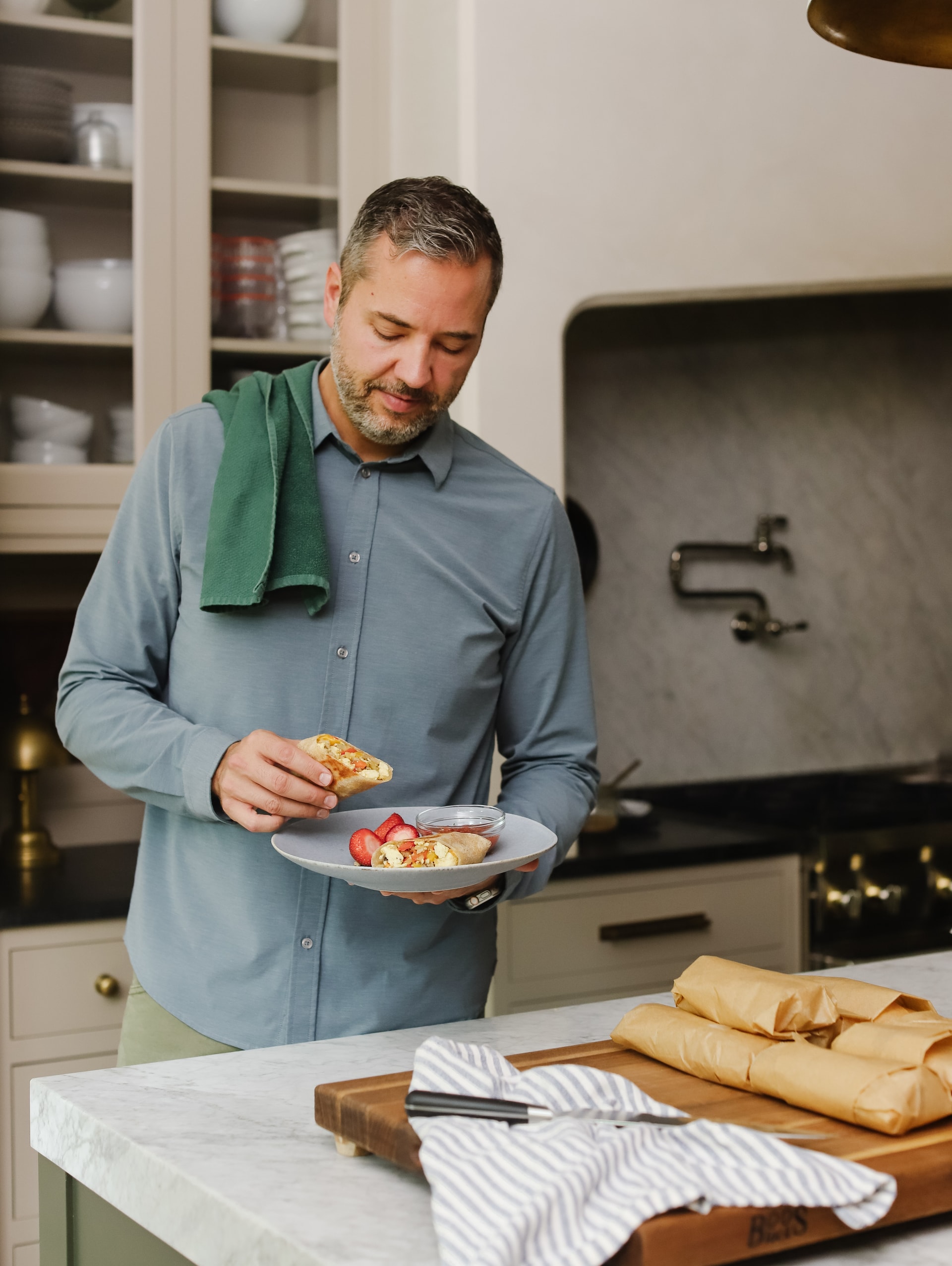 Chris Loves Julia | Chris standing in the kitchen with a plate of breakfast burritos and strawberries