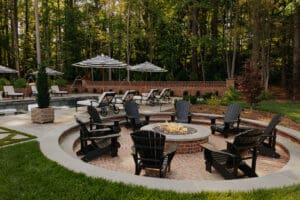 Fire pit outdoors surrounded by black adirondack chairs
