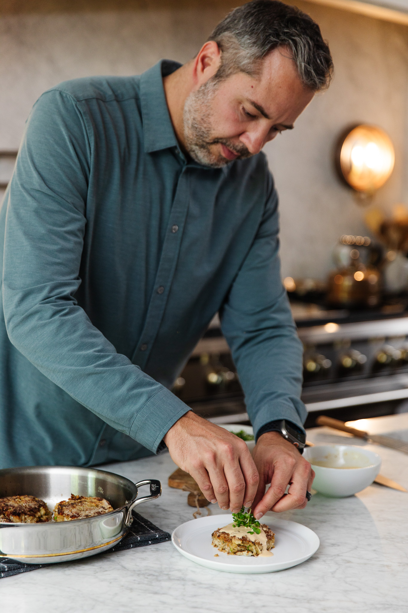 Chris Loves Julia | Chris plating the crab cakes with easy remoulade sauce topped with microgreens