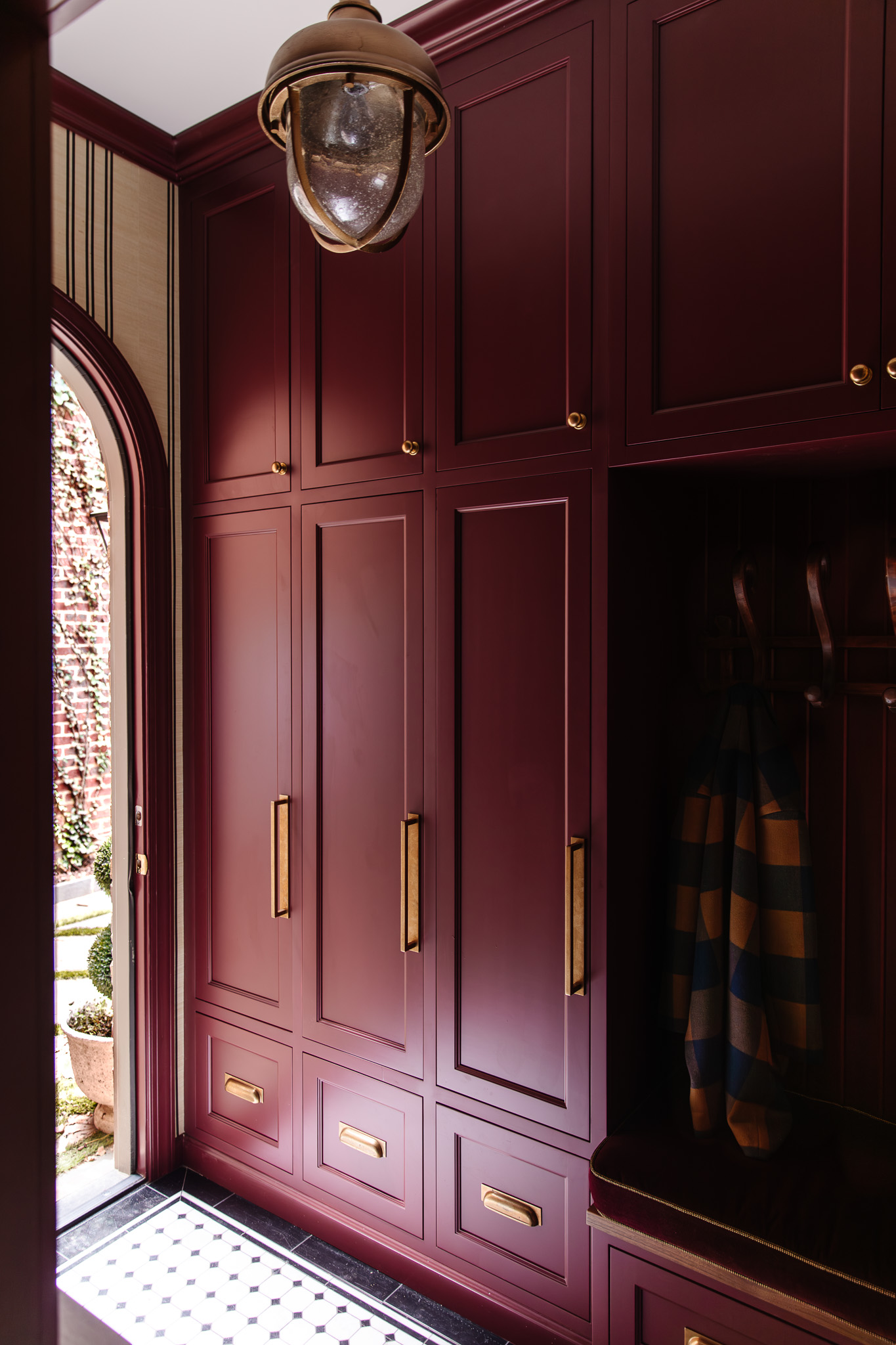 Chris Loves Julia | Moody dark red mudroom with gold locker accents