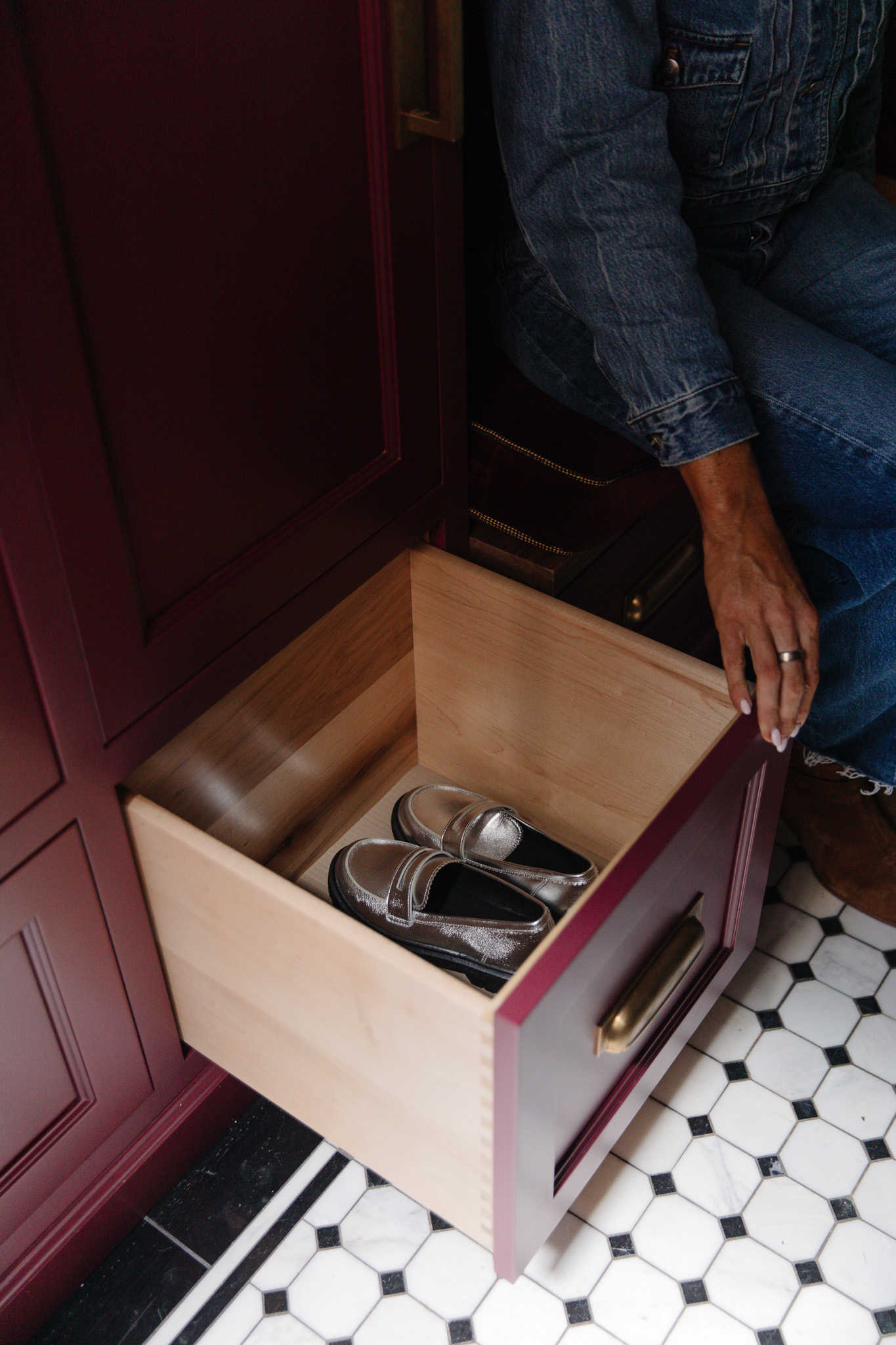 Chris Loves Julia | Moody dark red mudroom with a lower drawer open to reveal a pair of silver kids' loafers