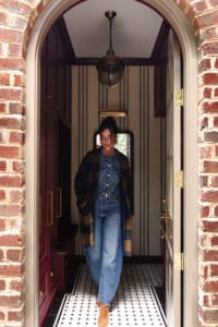 Julia walking out of the mudroom in denim barrel jeans, a denim top and jacket