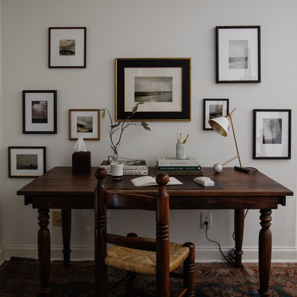 A scattered wall of Framebridge frames of antique seaside photos above a desk