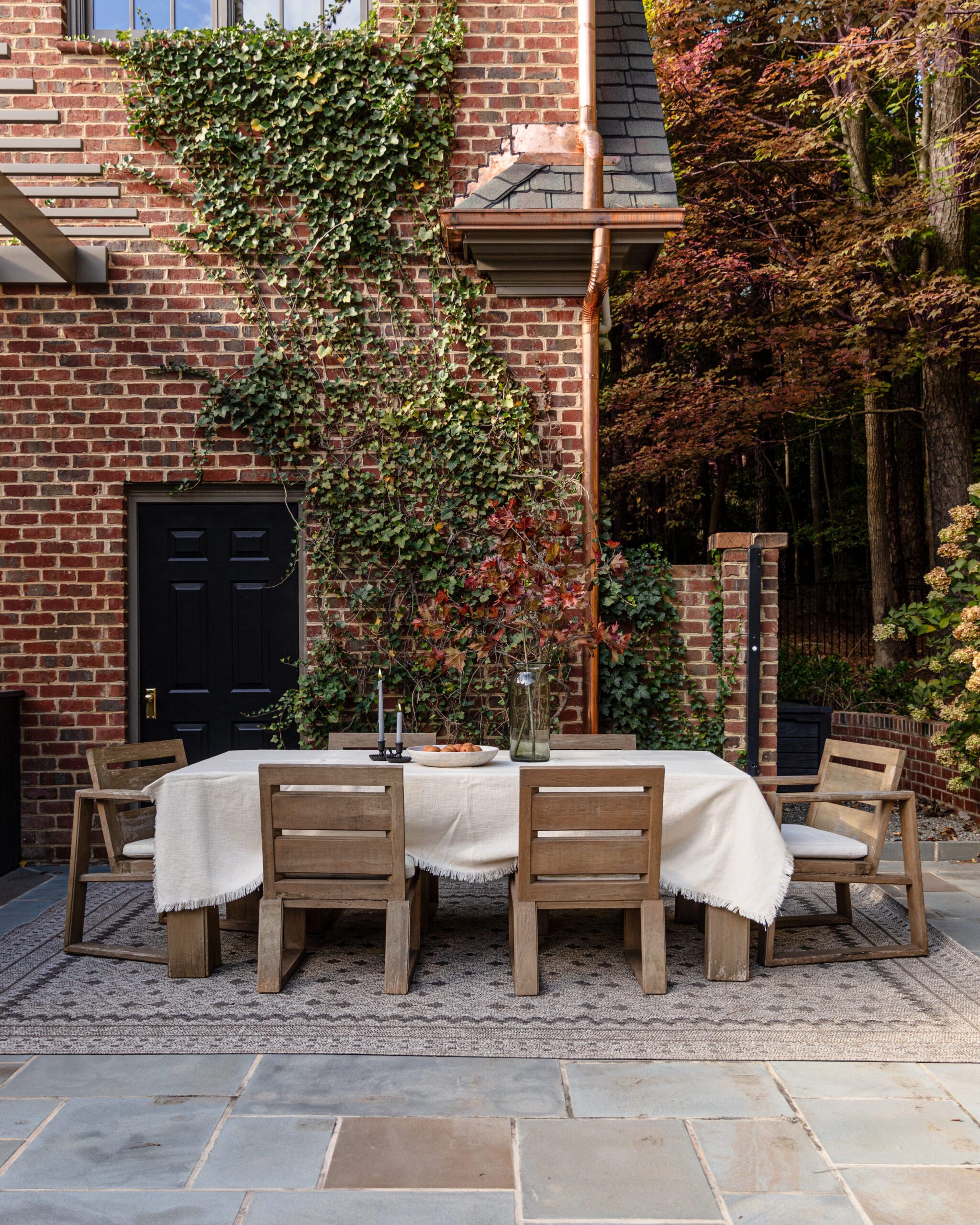 Outdoor dining table with cream tablecloth over a beautiful beige geometric Chris Loves Julia x Loloi outdoor rug