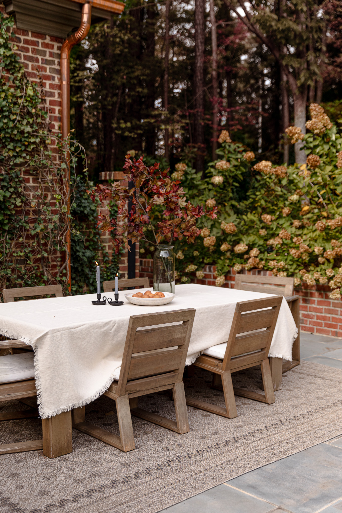 Outdoor dining table in fall over a neutral, geometric outdoor rug on pavers