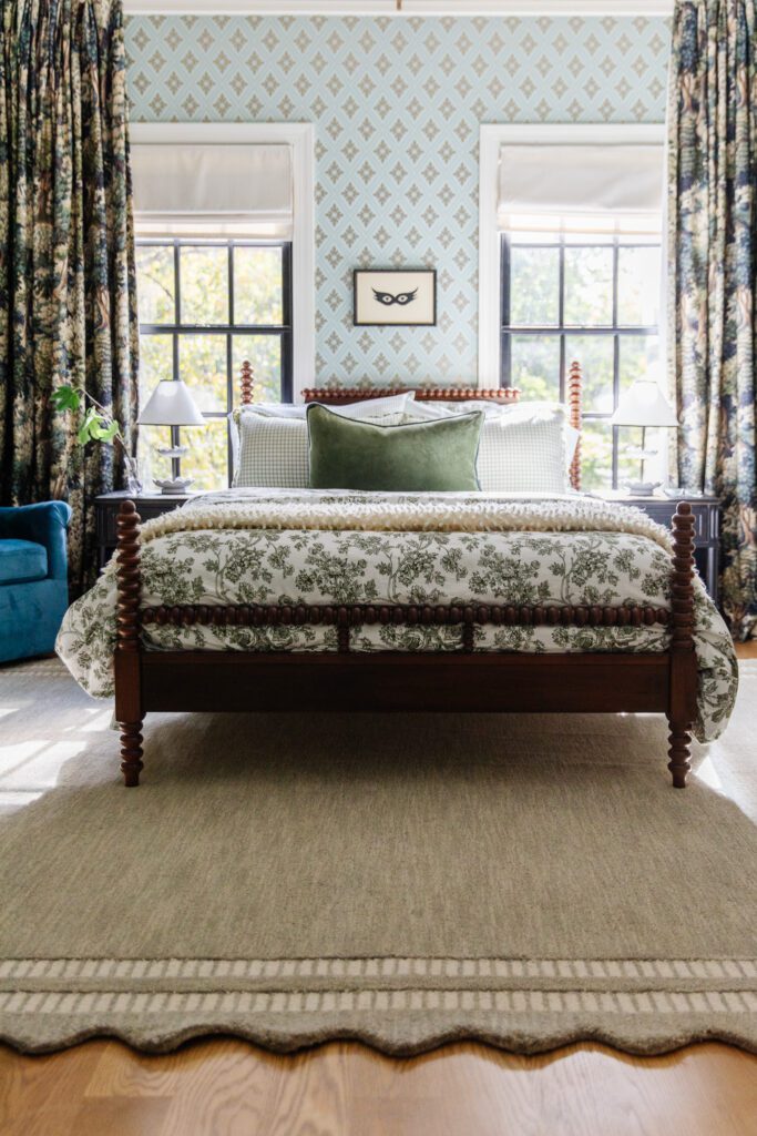 Bed over a scalloped-edge rug with a framing stripe on hardwood floors