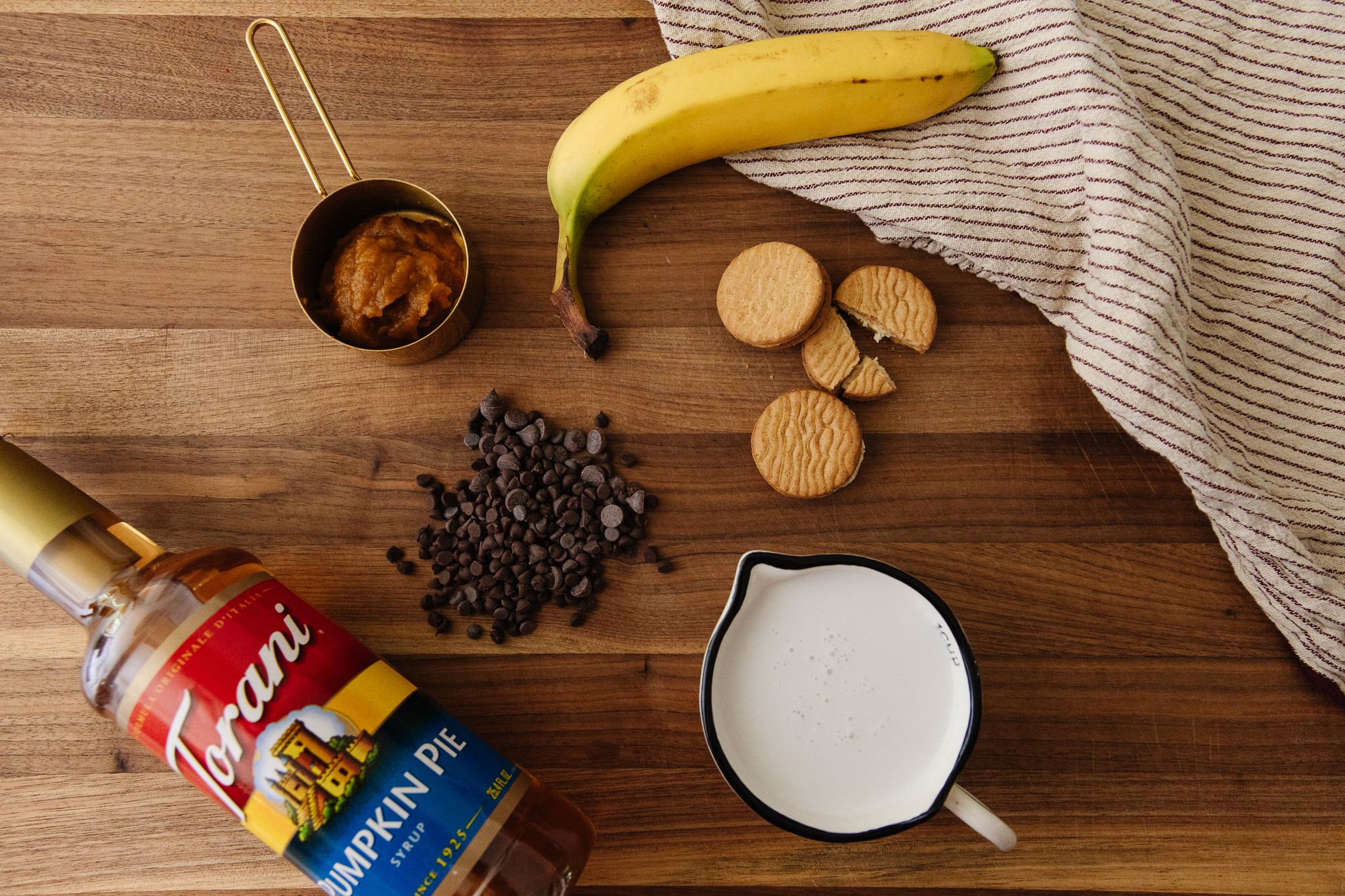 Counter with ripe banana, chocolate chips, cookies, pumpkin pie syrup, milk and pie mix