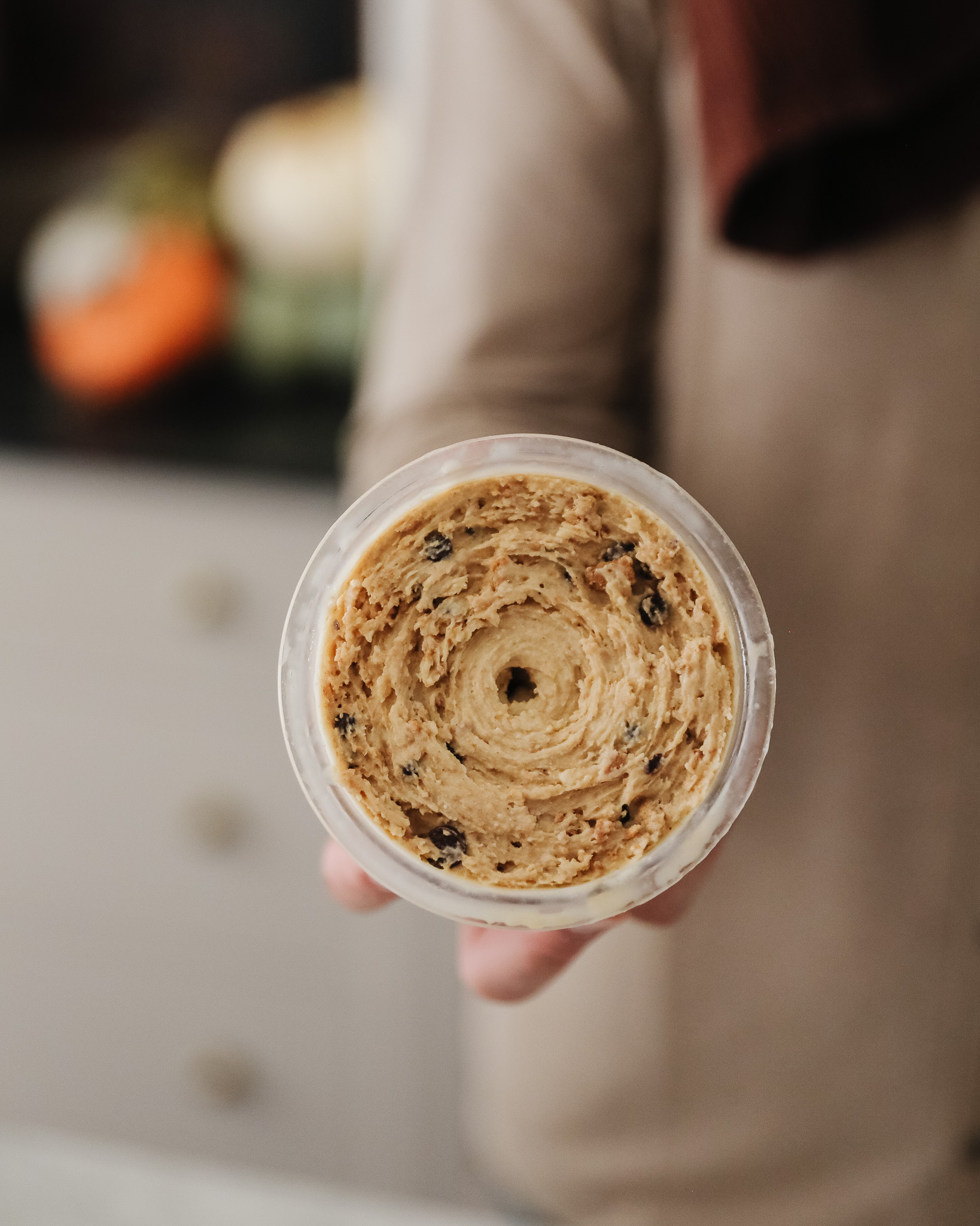 A person showing the top of a container filled with pumpkin chocolate chip ice cream