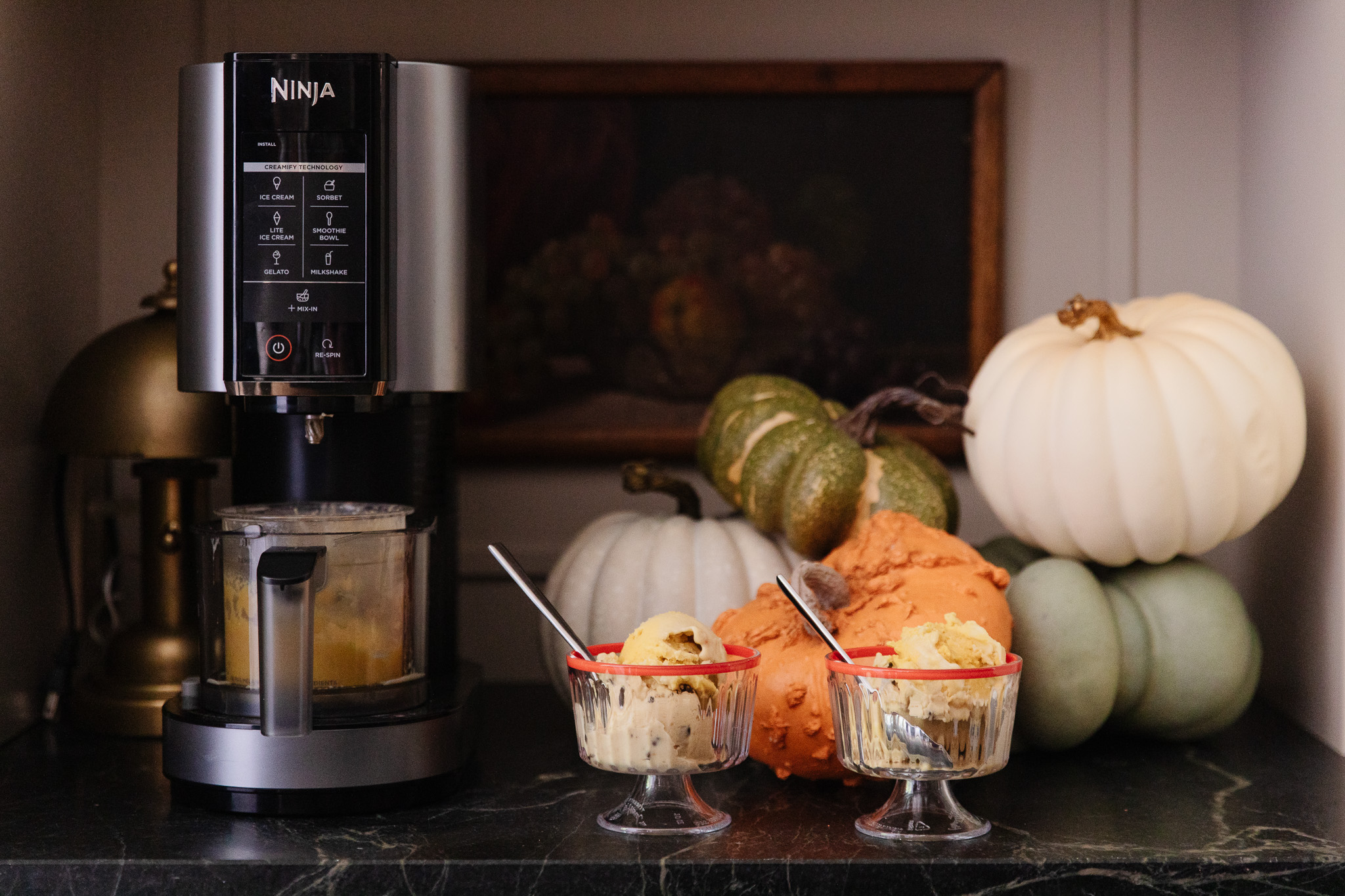 A counter topped with two cups filled with ice cream next to a Ninja CREAMi.