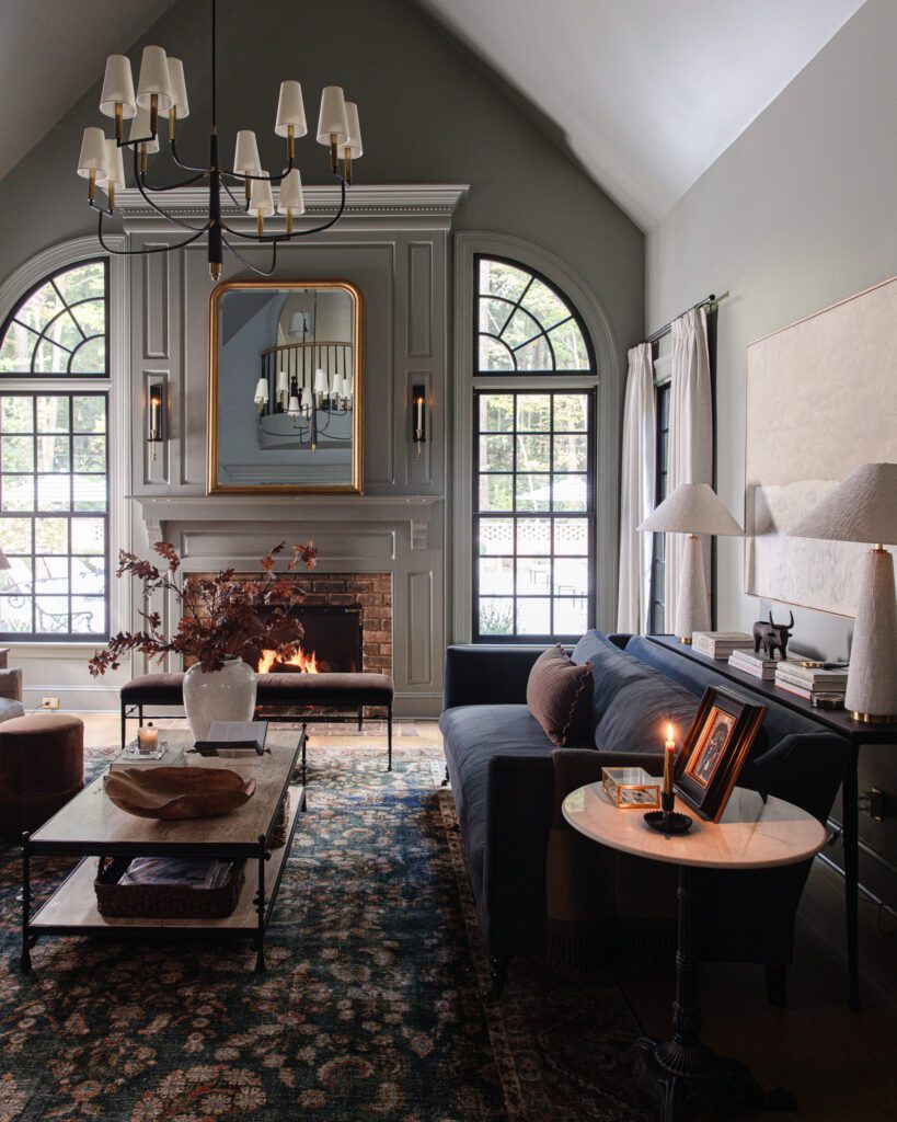 Living room with blue couch and vintage-looking navy and red rug in front of a fireplace