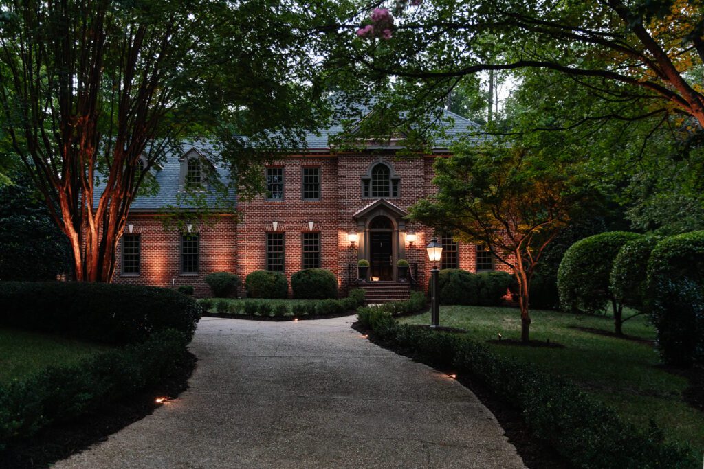 Brick home at night with driveway path lighting