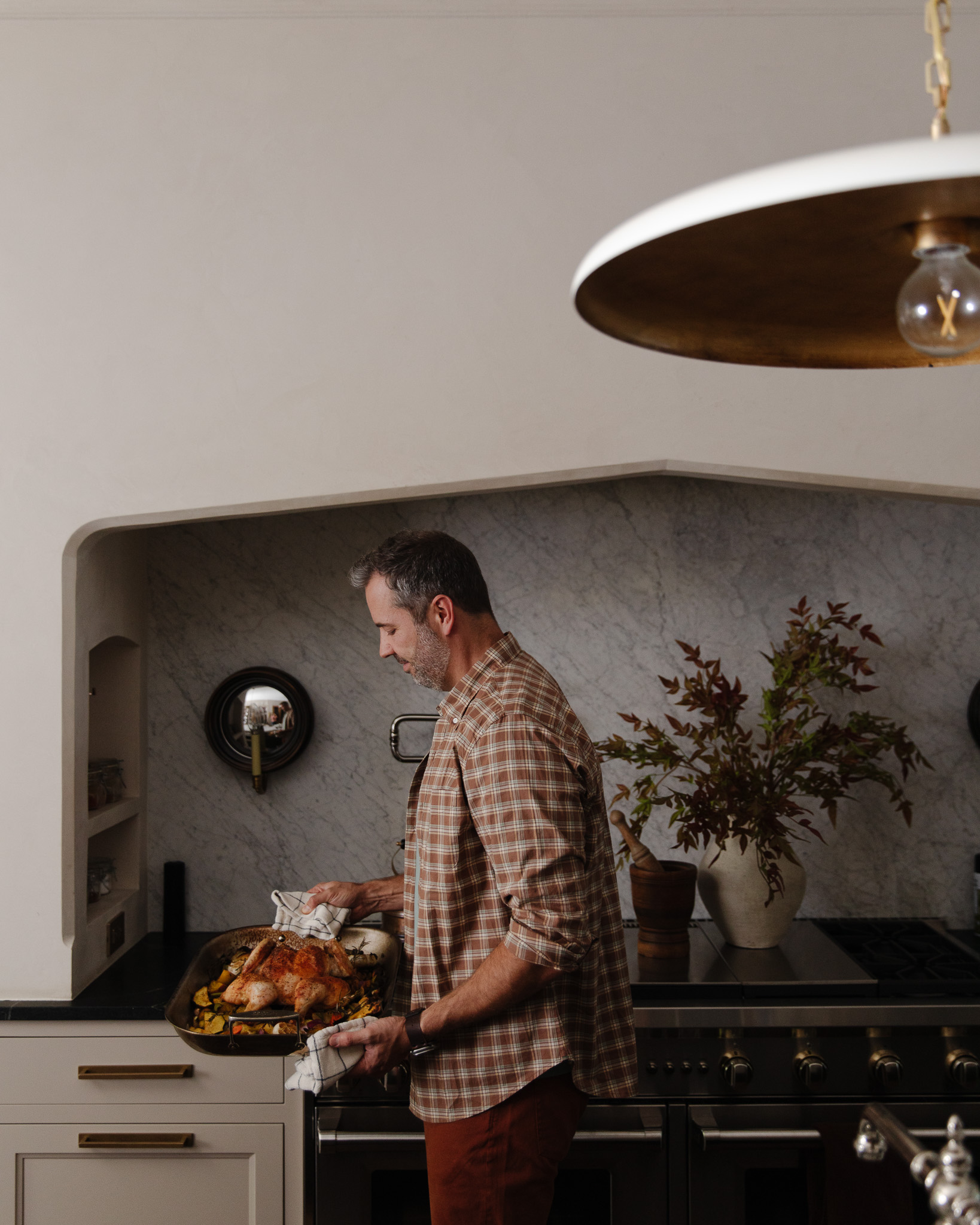 Chris holding a roasting pan with a whole chicken and vegetables