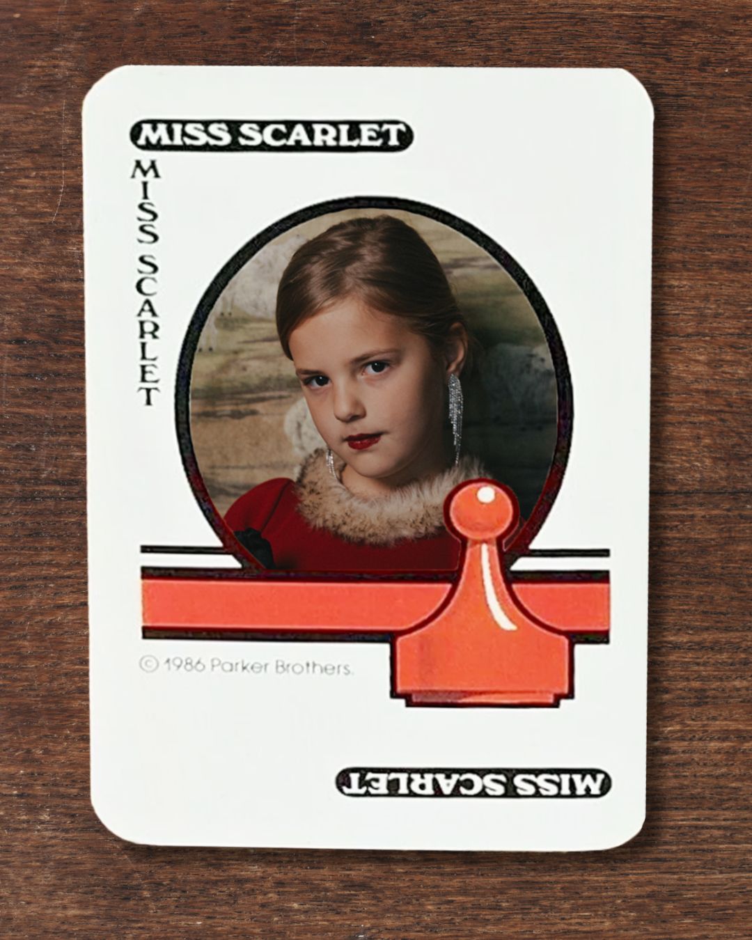 Girl dressed as Miss Scarlet on a classic playing card from Clue: The Game.