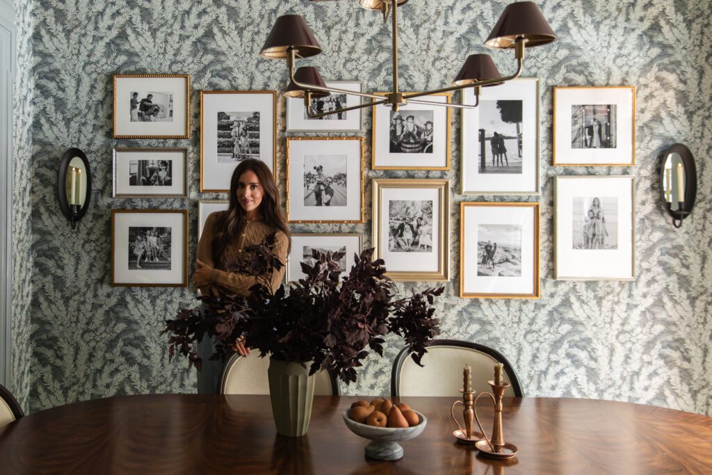 Julia Marcum in front of a gallery wall of antique gold Framebridge frames filled with B&W photos