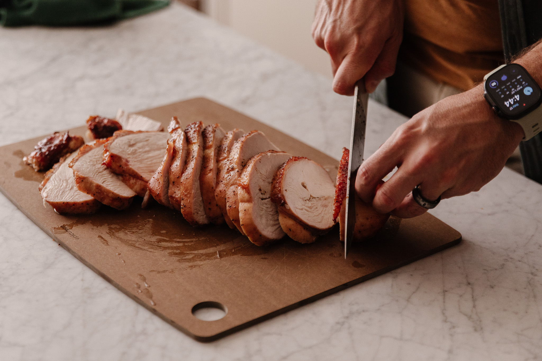 Hands slicing a seasoned turkey breast on a cutting board