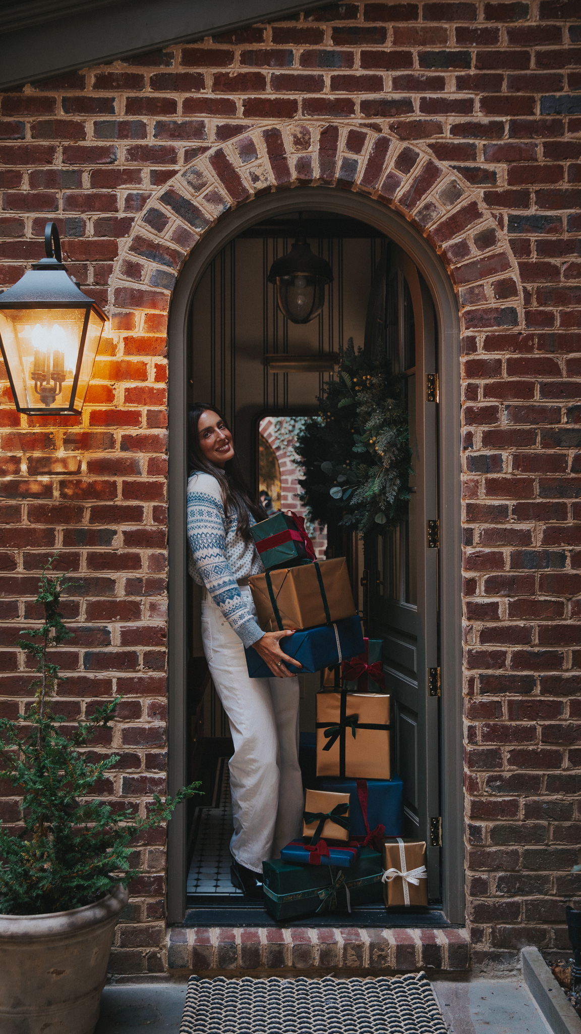 Julia holding a stack of beautifully wrapped presents in a doorway