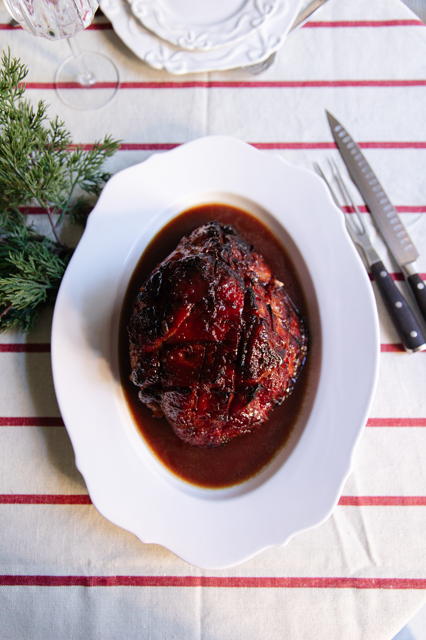 Caramelized cranberry-glazed ham roast on a white platter